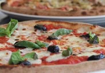 Pizza con mozzarella, pomodoro, olive nere e basilico